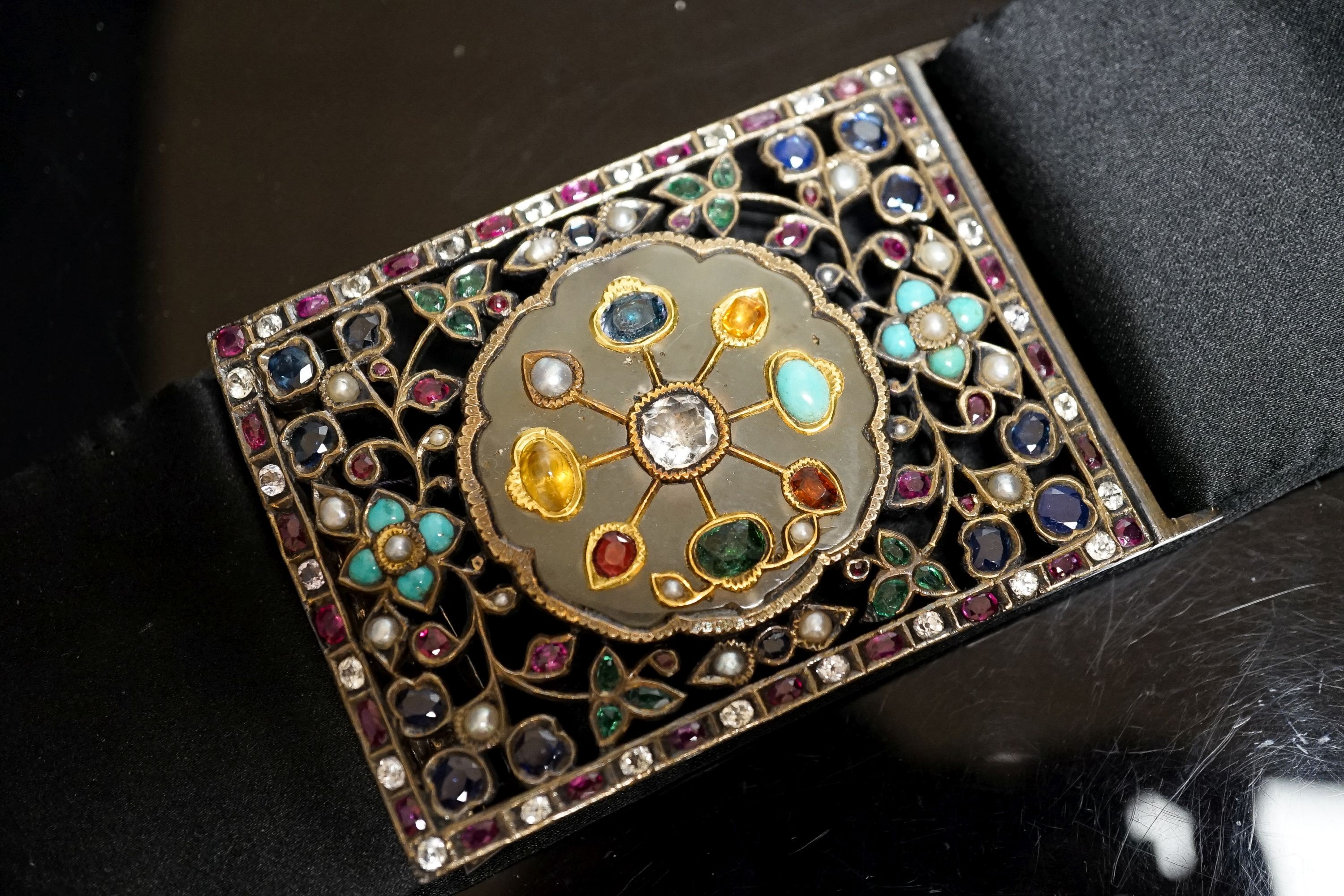 An Indian multi gem set belt buckle, mounted on a black sash belt, buckle 8cm.